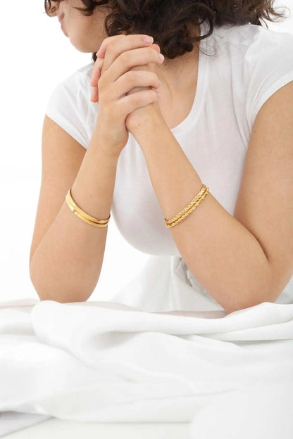 Woman wearing 22K gold bangle eclisse curve collection demonstrating comfortable curved fit on wrist, Chrysus Golds
