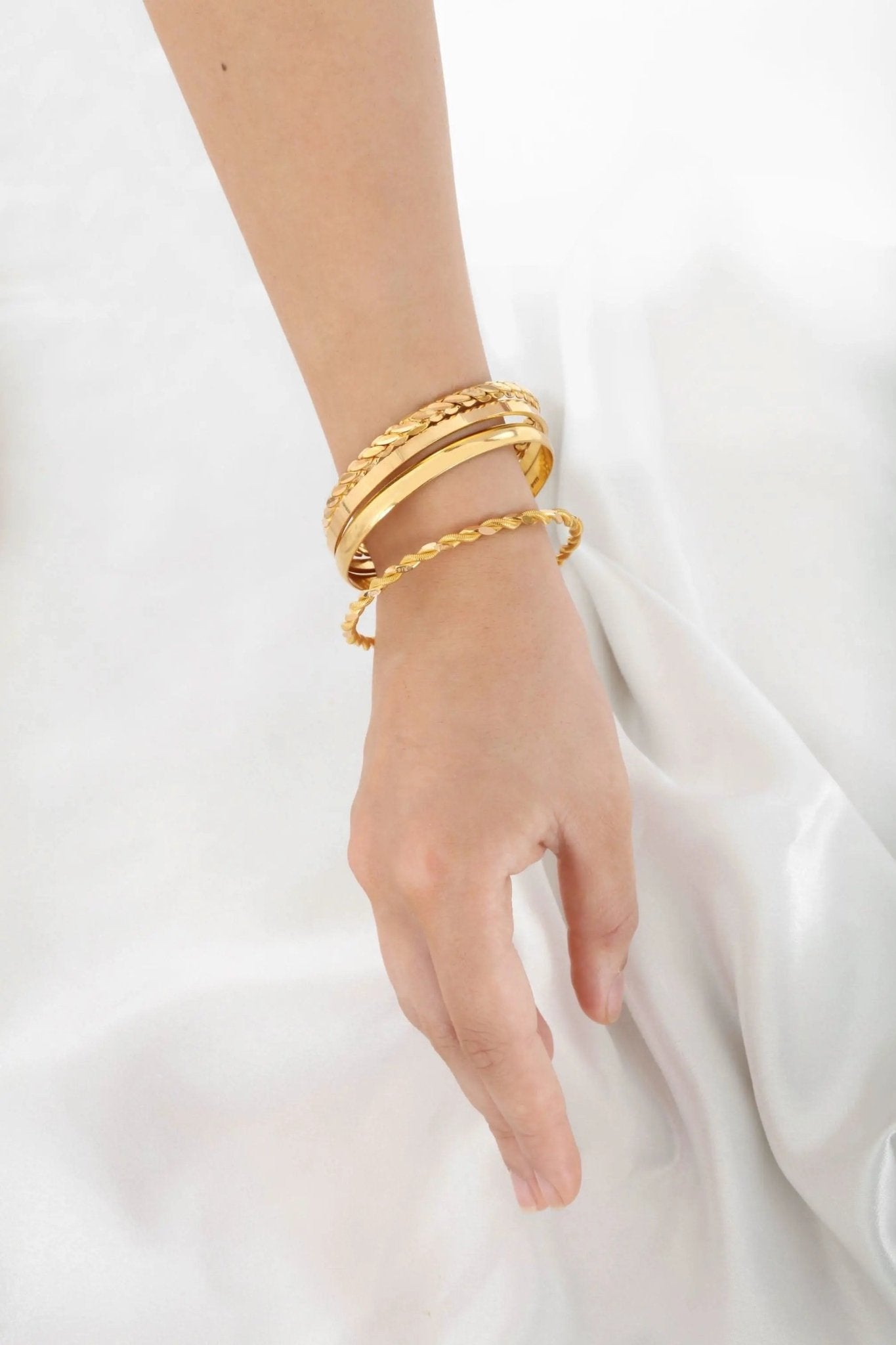 Woman wearing 22K gold bangle triple twirl collection, showcasing elegant fit and design on arm, Chrysus Golds